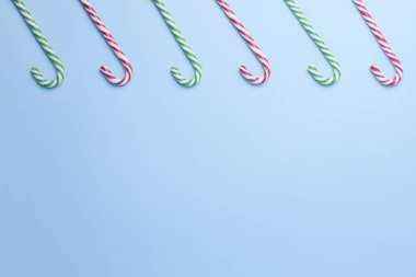 Mavi arka planda beş çizgili çubuk şeker. Noel, yeni yıl, tatil. Minimalizm bayramı konsepti düzleşmişti. Boşluğu kopyala. 