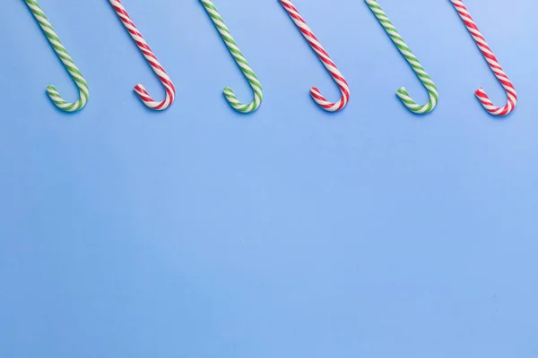 Cinco palos de caramelo rayados alineados sobre un fondo azul. Navidad, Año Nuevo, vacaciones. Plano yacía minimalismo concepto de vacaciones. Copiar espacio. — Foto de Stock