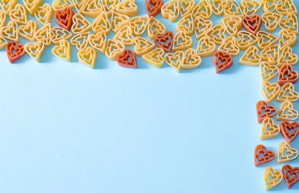 Telaio realizzato in pasta a forma di cuore su una superficie blu. Il concetto di San Valentino. FlatLay. Ricevuto. Vista dall'alto. — Foto Stock