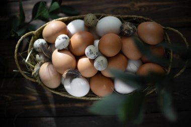 Paskalya israfı. Tavuk ve bıldırcın yumurtaları ahşap bir masada sepetin içinde. Paskalya 'nın sıcak dini bayramı, çevre dostu dekor kavramı. Çiftlik ürünleri