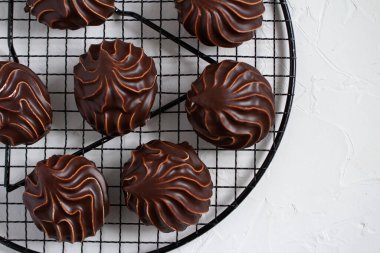 Beyaz masada yuvarlak bir rafta, çikolatada beyaz şekerlemeler.. 