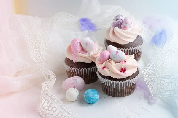 Tre cupcake di cioccolato pasquali con ripieno di caramello e decorazione di piccole uova di Pasqua dal marzapane sullo sfondo bianco. Focus selettivo — Foto Stock