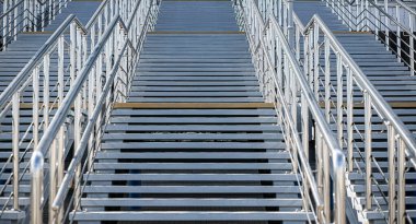 Gri beton basamakları ve metal parmaklıkları olan bir merdiven. Şehir mimarisinin bir unsuru