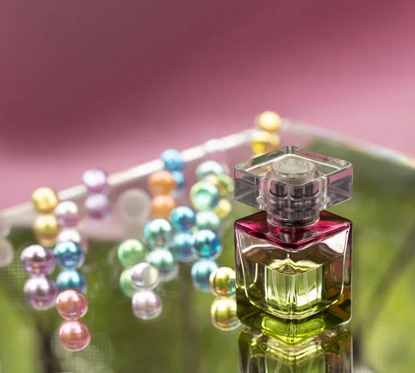 Butelka perfum ze szklanymi kulkami na różowym tle. Perfumy, kosmetyki, kolekcja substancji zapachowych. — Zdjęcie stockowe