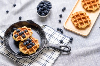 Ev yapımı waffle yaban mersini ve tavaya benzeyen bir tabakta krema..