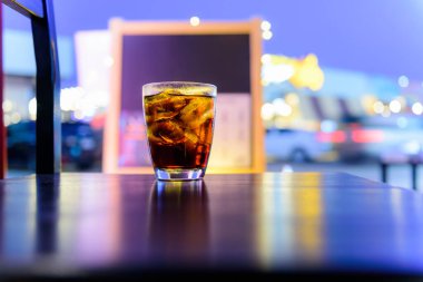 Gece vakti masada Bokeh 'le birlikte bardakta soda ya da kola içmek.