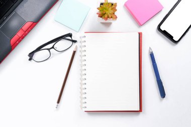 Üst görünüm ya da Düz görünüm iş için çalışma alanının fotokopi alanı, dizüstü bilgisayar, kalem, not defteri, kahve fincanı, gözlük ve cep telefonu beyaz masa arkasında izole edilmiş.