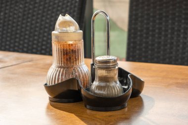 Baharatlı biber şişesi kavanozu açık hava restoranındaki ahşap masada. 