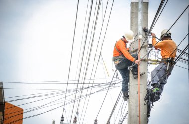 Elektrikçiler elektrik hatlarını kurmak ve onarmak için elektrik direklerine tırmanıyorlar..