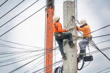 Elektrikçiler elektrik hatlarını kurmak ve onarmak için elektrik direklerine tırmanıyorlar..