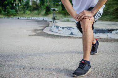 Genç koşucu parkta koşmadan önce ısınıyor.