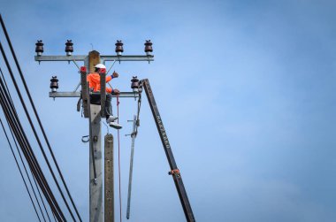 Elektrikçiler elektrik hatlarını kurmak ve onarmak için elektrik direklerine tırmanıyorlar..