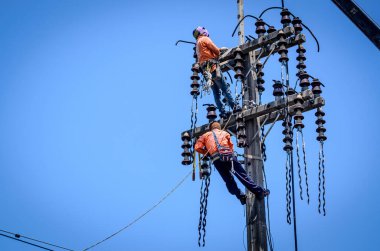 Samut Sakhon, Tayland - Mayıs 2019: Elektrikçiler elektrik hatlarını kurmak ve onarmak için elektrik direklerine tırmanıyorlar. 19 Mayıs 2019 'da Samut Sakhon, Tayland' da.