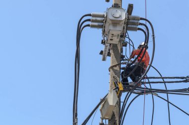 Elektrikçiler elektrik hatlarını kurmak ve onarmak için elektrik direklerine tırmanıyorlar..