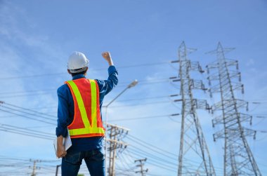 Başarılı mühendisler mavi arkaplanda elektrik direğine karşı duruyorlar..