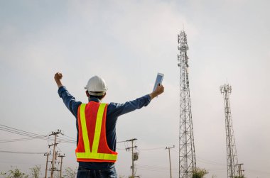 Başarılı erkek mühendis iletişim kulesinin arka planında duruyor.