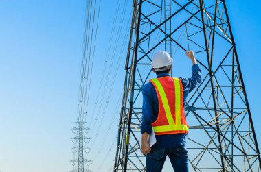 Başarılı mühendisler mavi arka planda elektrik direklerine karşı dururlar..