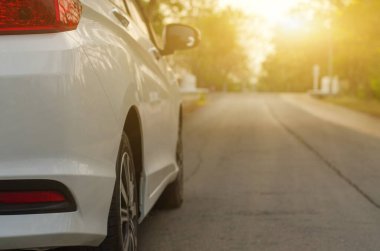 Beyaz araba caddeye park ediyor.