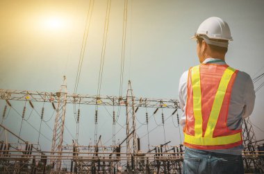 Başarılı elektrik mühendisleri mavi gökyüzü arka planında istasyona karşı duruyorlar..