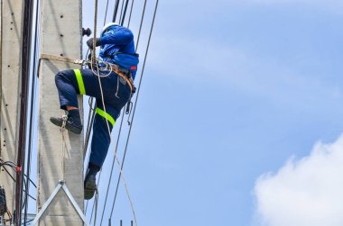 Elektrikçiler elektrik hatlarını kurmak ve onarmak için elektrik direklerine tırmanıyorlar..