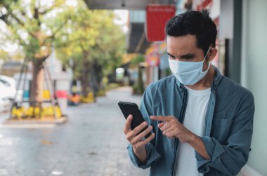 Asyalı erkekler koronavirüsün yayılmasını önlemek için maske takarlar. Hayatlarında cep telefonları, sosyal mesafeler, yeni normaller kullanarak..