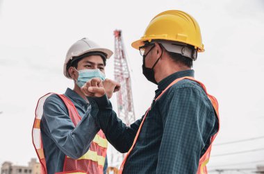İki mühendis açık hava koronavirüsünden kaçınmak için dirseğe vurmuş. Arkadaşlar koroner salgın sırasında yeni bir selamlama yöntemi gösterdiler. Sağlık hizmeti konsepti. Sosyal Mesafe.