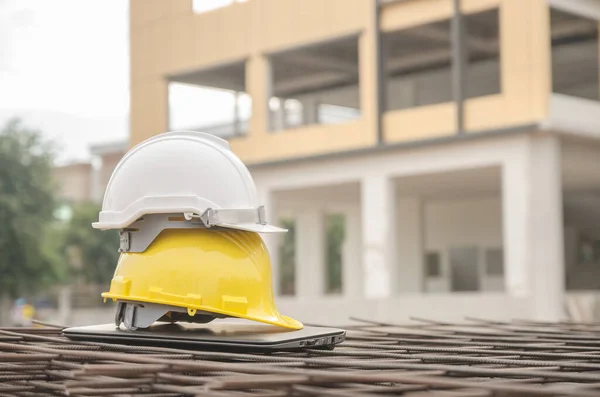white and yellow safety helmet at construction site with building background