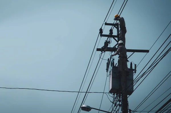 Electricians are climbing on electric poles to install and repair power lines.