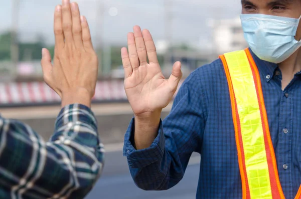 Two engineers raised the palm to greet to avoid the coronavirus outdoors to demonstrate a new method of greeting during the coronary heart disease epidemic. Health care concept, Social distancing between people, New normal