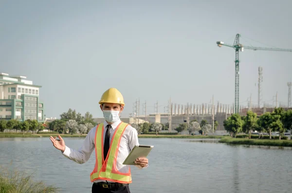 Engineers wear a helmet and holding tablet with monitoring the construction site.