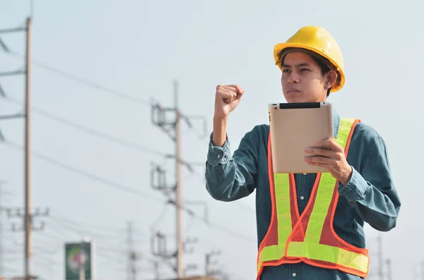 Electrical engineers standing at the job site, with tablet in hand.