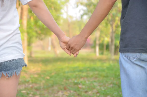 庭を歩いてリラックスして手を握っているカップル ロイヤリティフリーのストック画像