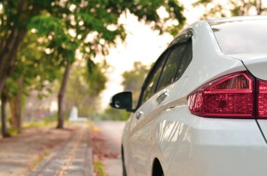 Yol kenarına park edilmiş beyaz bir araba.