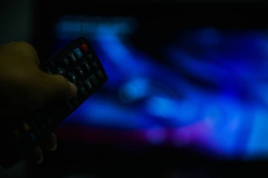 Kadının eli televizyonun uzaktan kumandasını tutuyor.