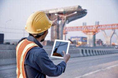 Yol inşaatında elinde tablet tutan bir adam mühendis.