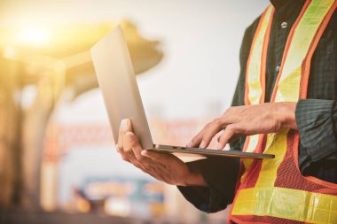 Sabah bir inşaat projesinde dizüstü bilgisayarla çalışan bir erkek mühendisin yakın çekimi..