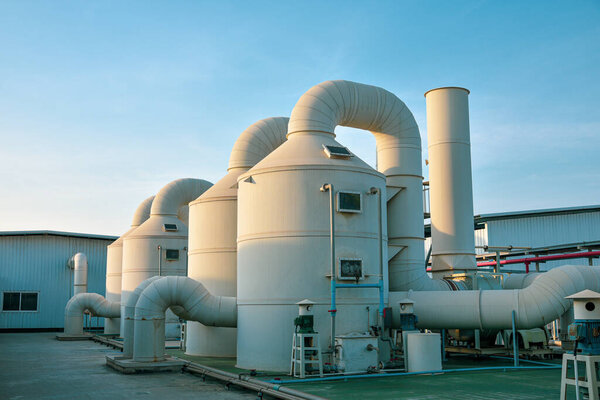 Промышленное оборудование для фильтрации загрязненных воздухом прудов с резервуарами и резервуарами для воды на голубом фоне неба.