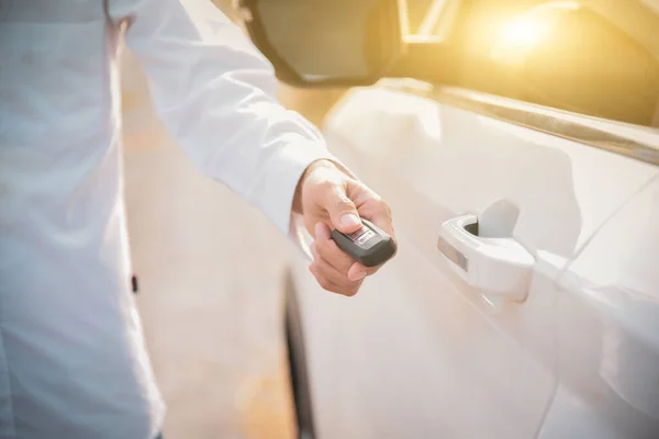 Car remote control by smart key, Hand holding smart key to lock doors of white car