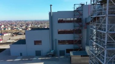 Metal parmaklıkları olan büyük gri sanayi binası.