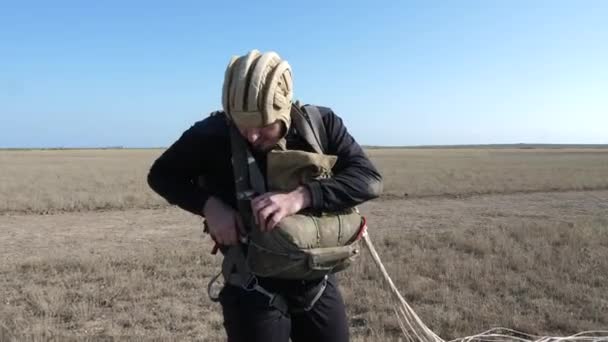 Nervöser Fallschirmspringer mit khakifarbenem Helm löst Fallschirmtasche — Stockvideo