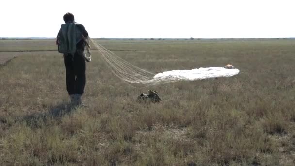 Fallschirmspringer taumelt in Fallschirmleinen, die auf Wiese liegen — Stockvideo