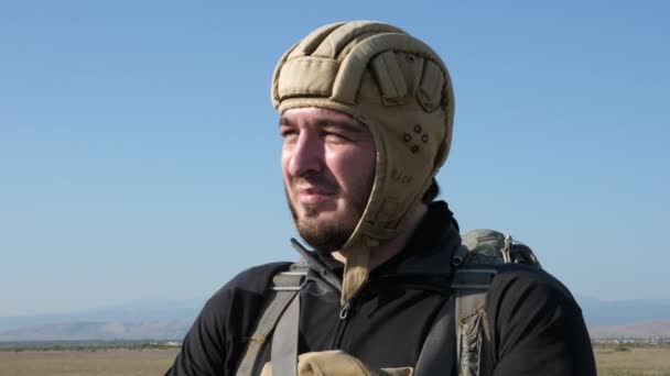 Нервный человек в шлеме готовится к прыжку с парашютом — стоковое видео