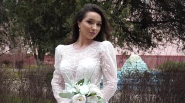 Şehir parkında dantelli uzun kollu gelinlikli bir bayan.