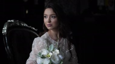 Dantelli elbiseli, eski koltukta buketi olan güzel bir gelin.