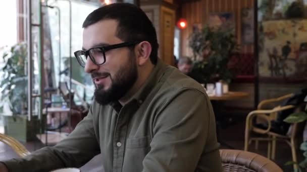 Hombre con gafas en camisa caqui habla con amigos en la cafetería — Vídeos de Stock