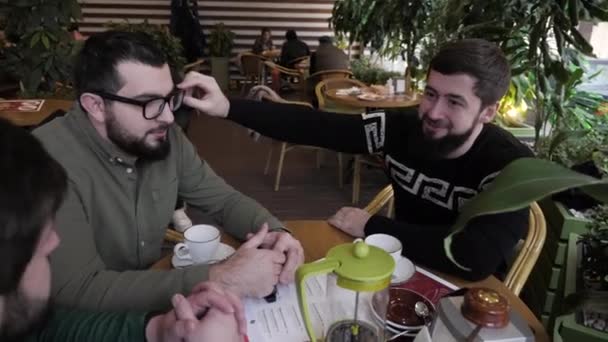 Друзья трогают новые стаканы молодого человека, проводящего время в кафе — стоковое видео
