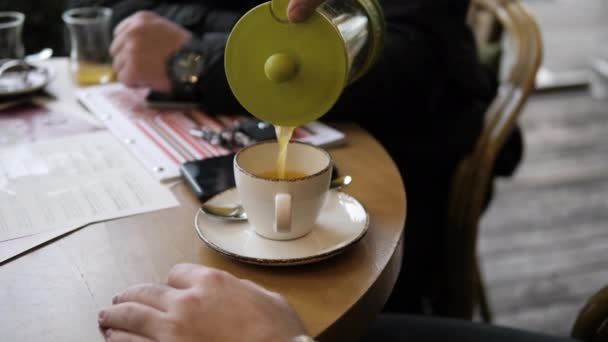 Mann füllt Tasse mit grünem Tee, sitzt mit Freunden im Café — Stockvideo