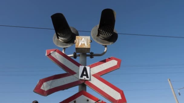 Znamení s kříženými liniemi a semafory proti jasné obloze — Stock video