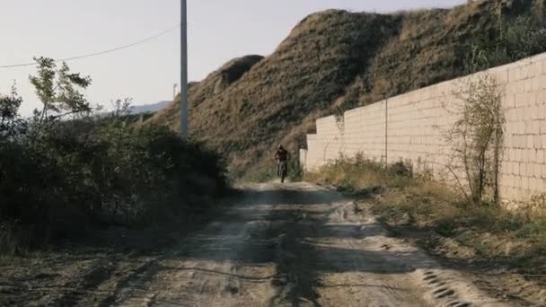 Motociclista em velocidades especiais de capacete ao longo da estrada terrestre — Vídeo de Stock