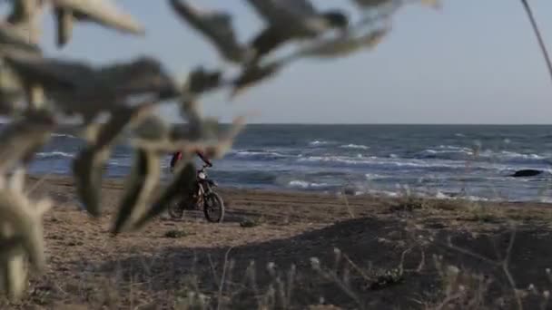 Cyklista ve speciální helmě jízdy podél písečné pláže proti moři — Stock video